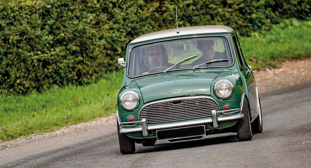Two people driving a small green Mini in the UK