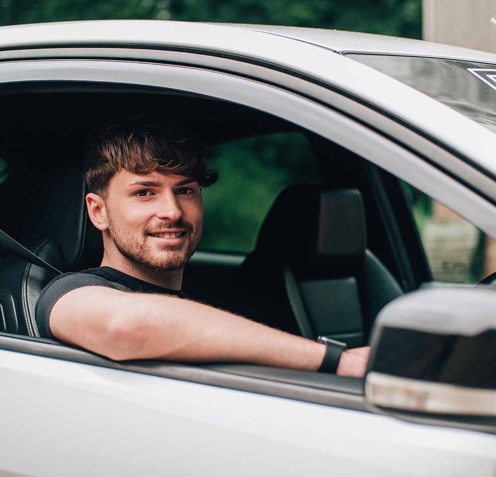 Man sitting in driver's seat smiling at camera