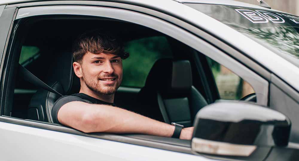 Man sitting in driver's seat smiling at camera