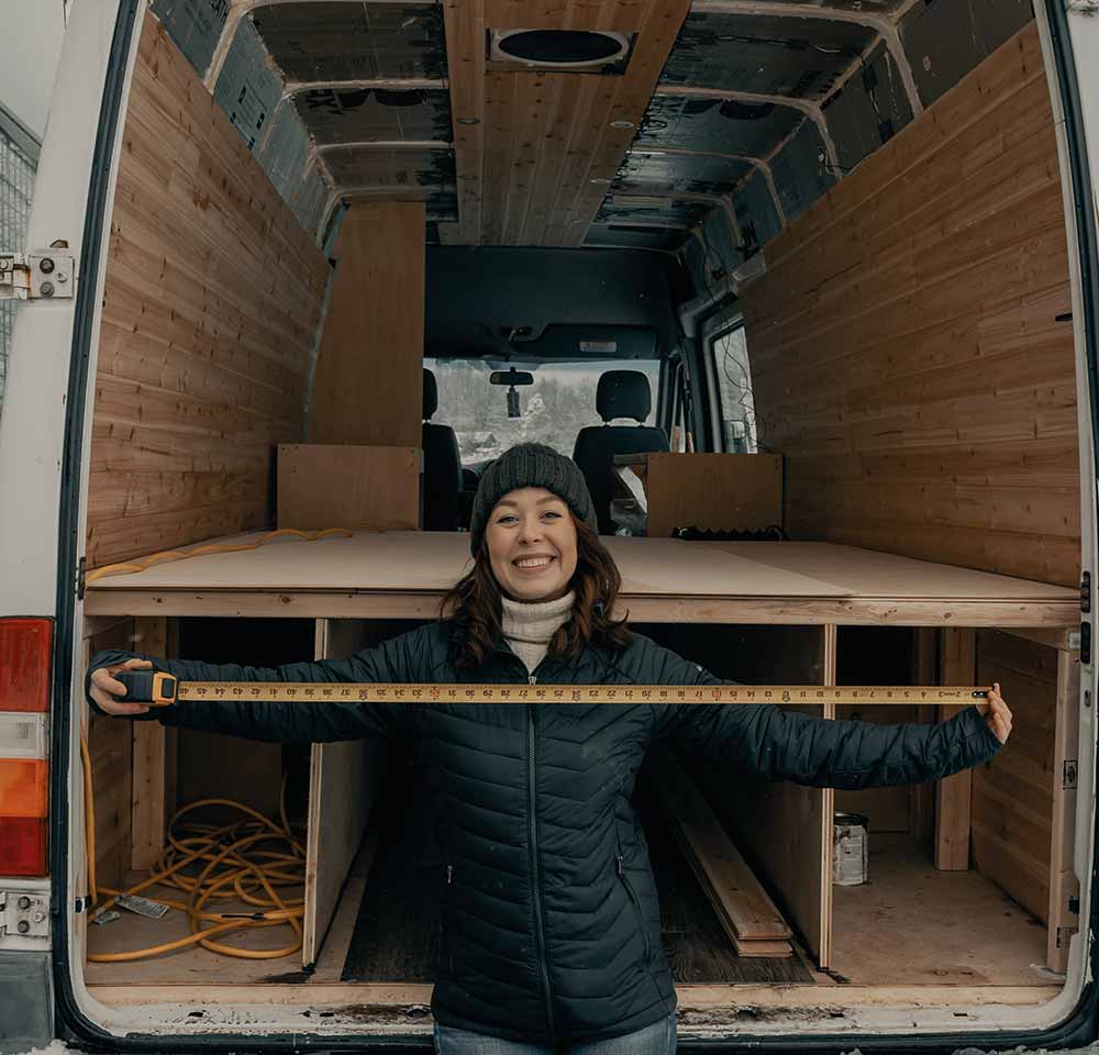 Woman with measuring tape in front of her converted van