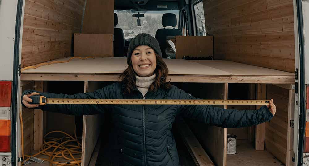 Woman with measuring tape in front of her converted van