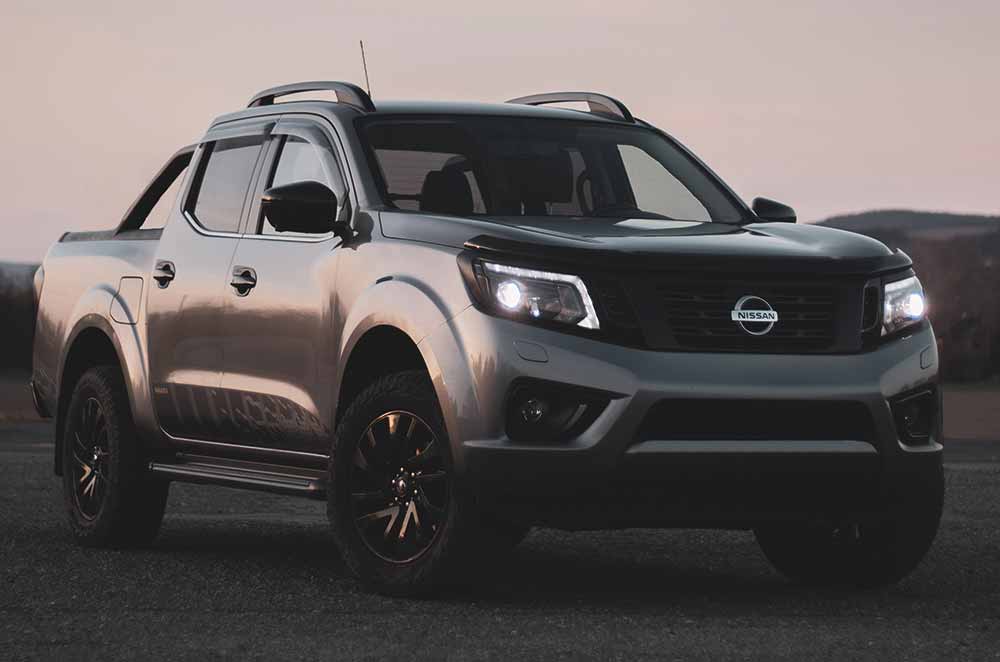 Modified Nissan pickup truck parked outside with headlights on