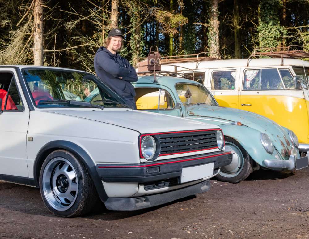 Man standing with his three classic cars