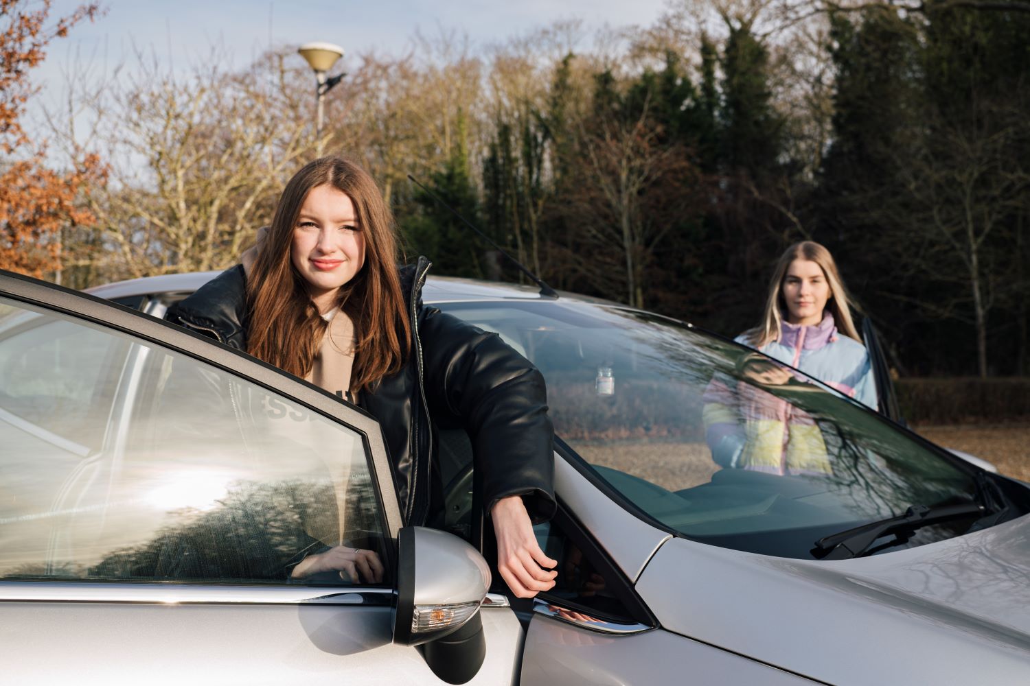 Young drivers standing just outside car