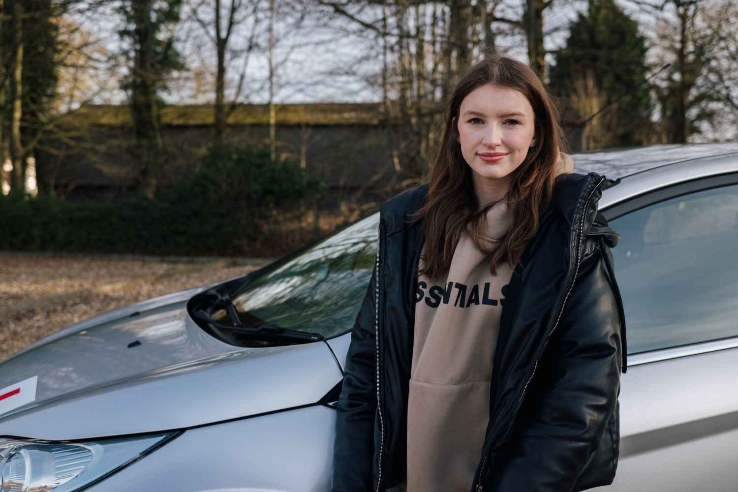 Young driver standing next to car and smiling