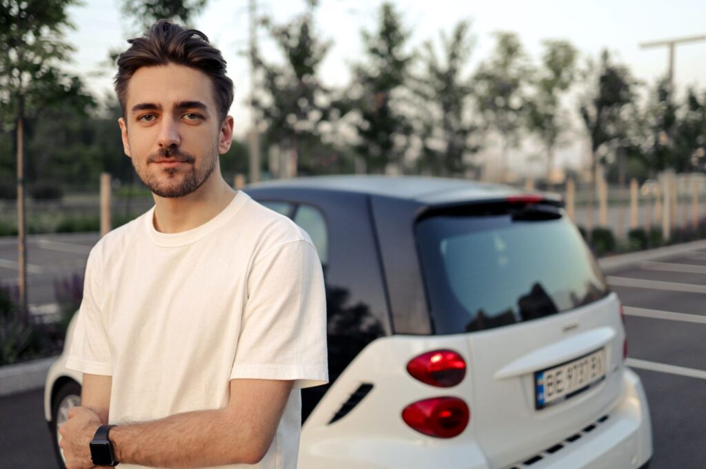 Young man standing next to car