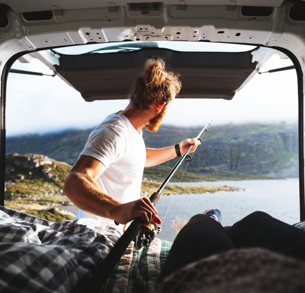 Man reaching for a fishing rod from a van