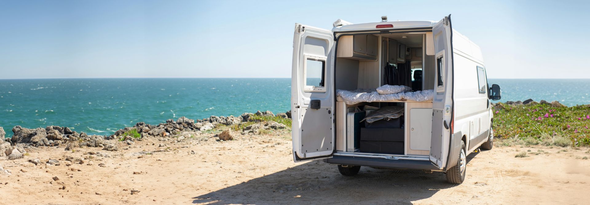 back of converted van parked next to the sea