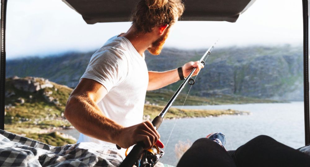 Man reaching for a fishing rod from a van