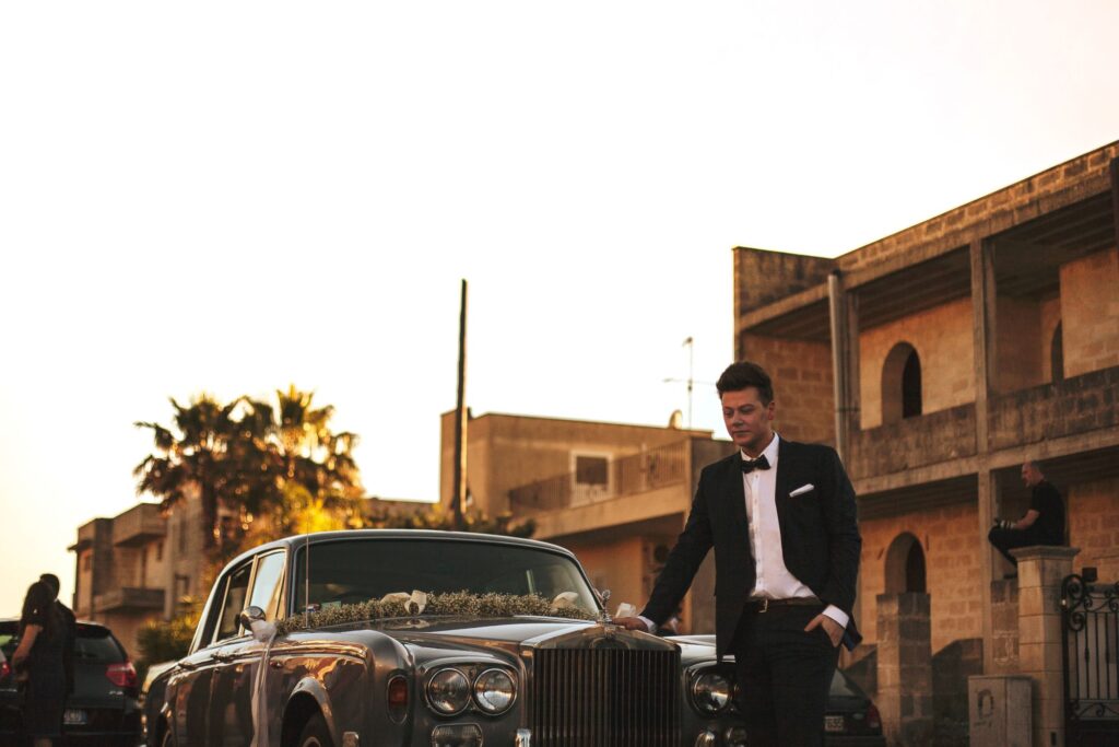 Man in suit next to classic car with wedding decorations