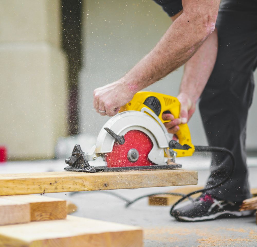 person using a power saw on a plank of wood