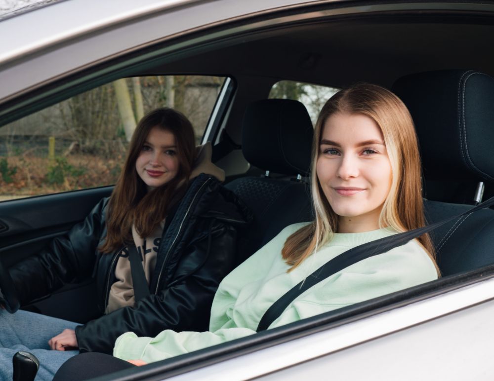 young drivers in a car smiling at the camera