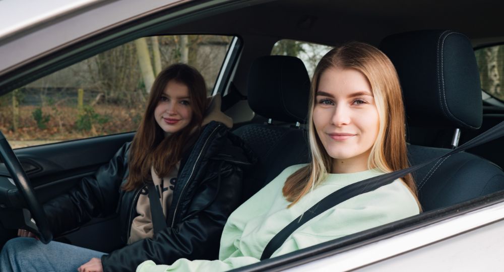 young drivers in a car smiling at the camera