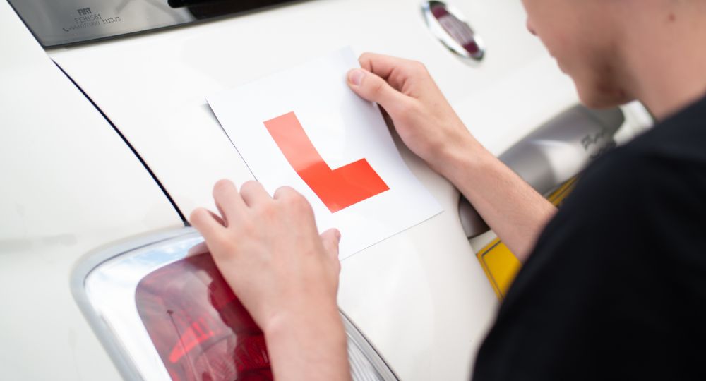Person attaching L plates to car