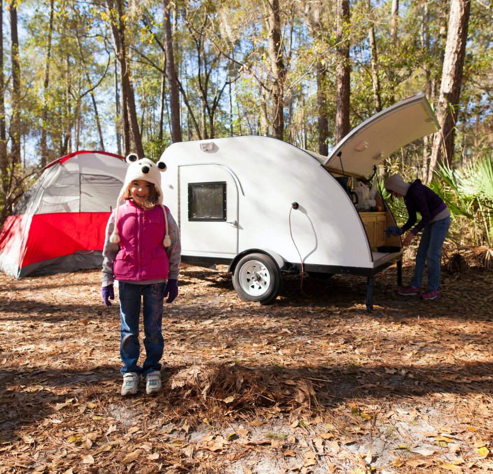 Child standing in front of trailer and tent