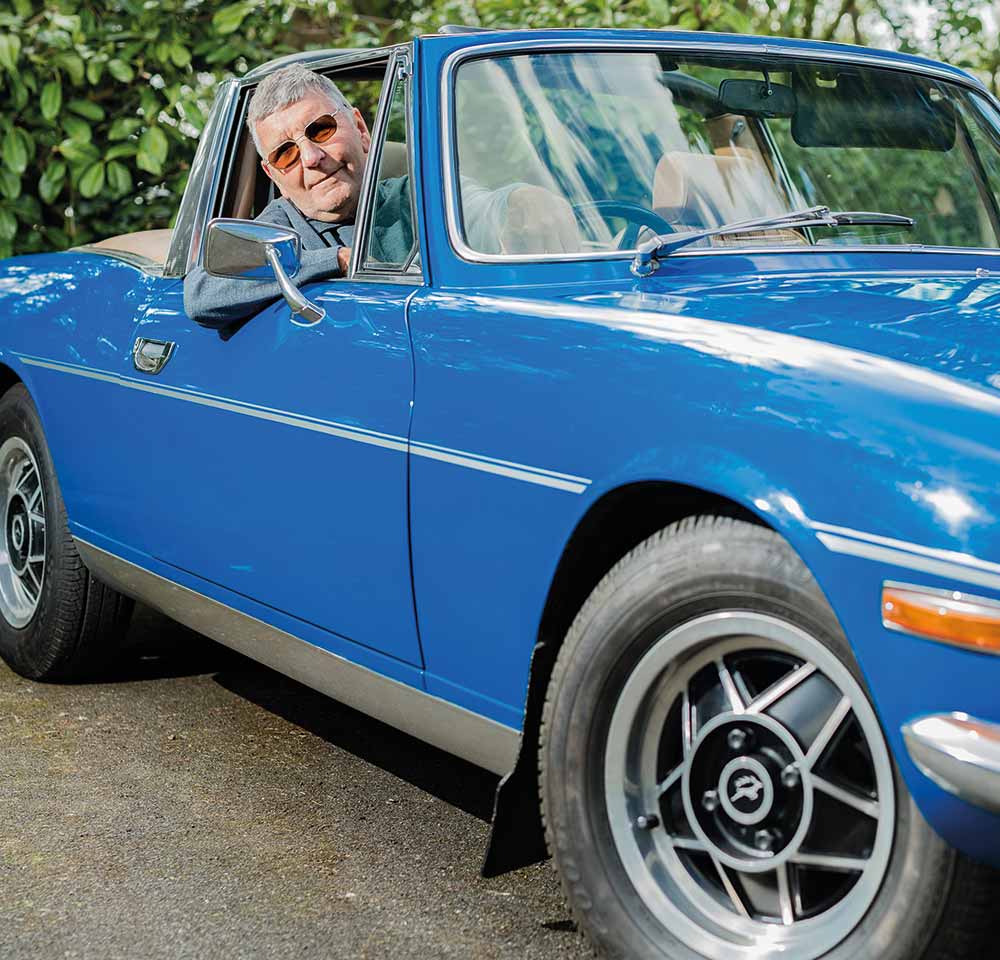 Man sitting in the driver's seat of his blue Triumph
