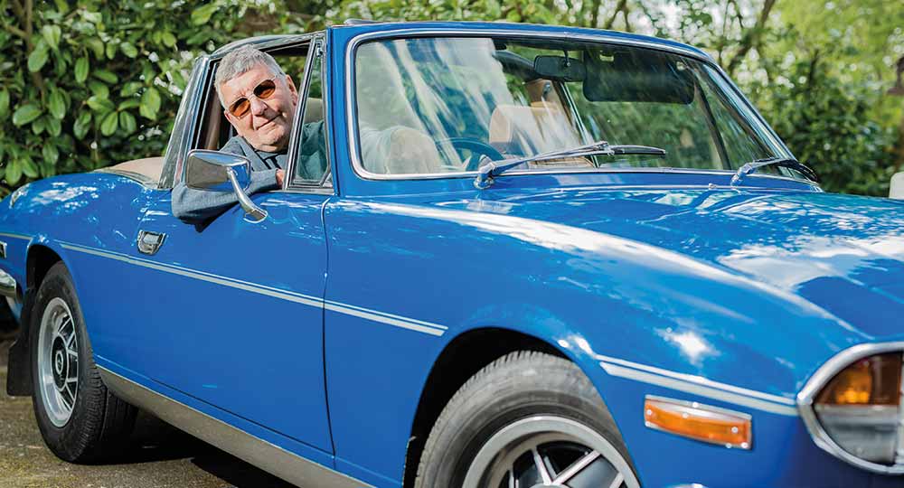 Man sitting in the driver's seat of his blue Triumph