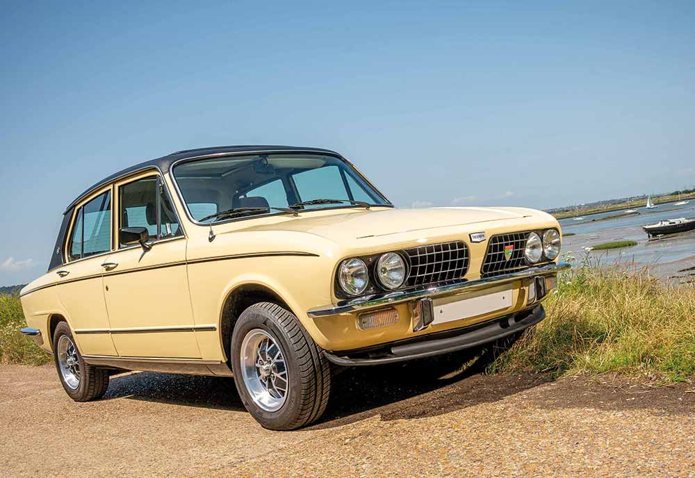 Yellow Triumph car pictured near water with sky in background