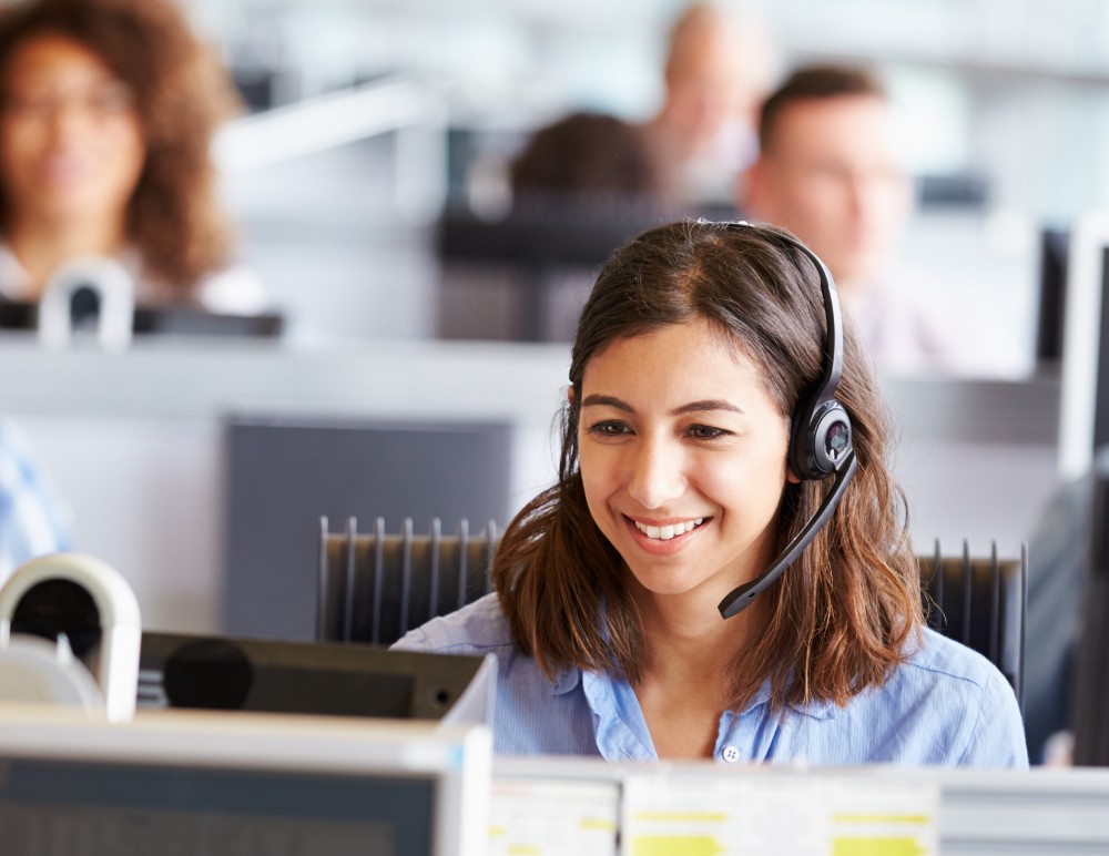 Smiling call centre clerk looking at a computer screen