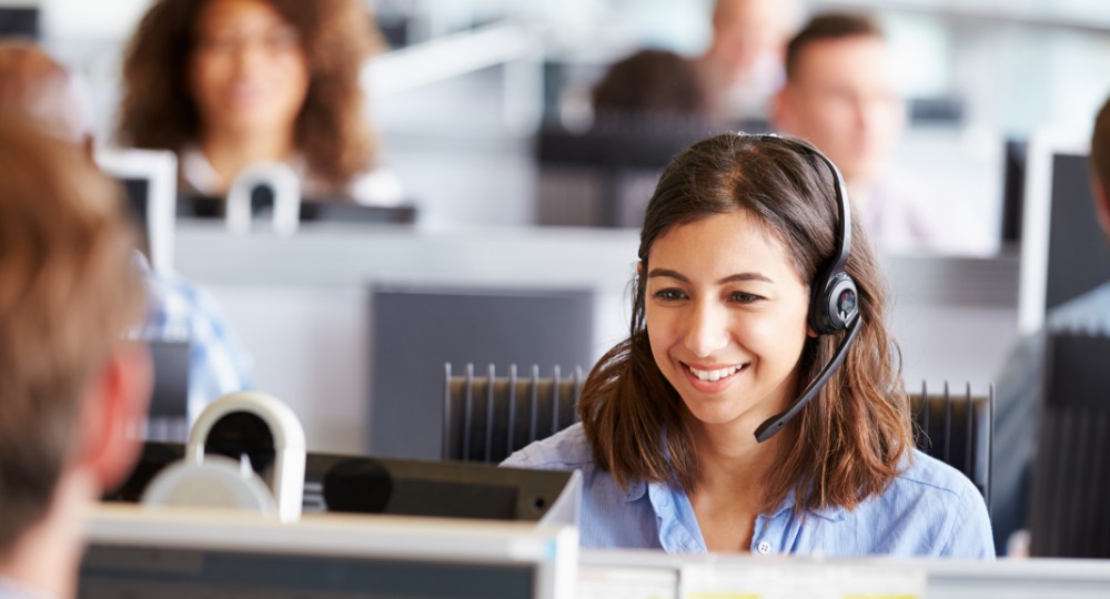 Smiling call centre clerk looking at a computer screen
